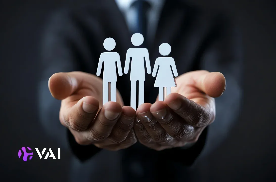 Open hands holding white paper figures of employees, symbolising human capital