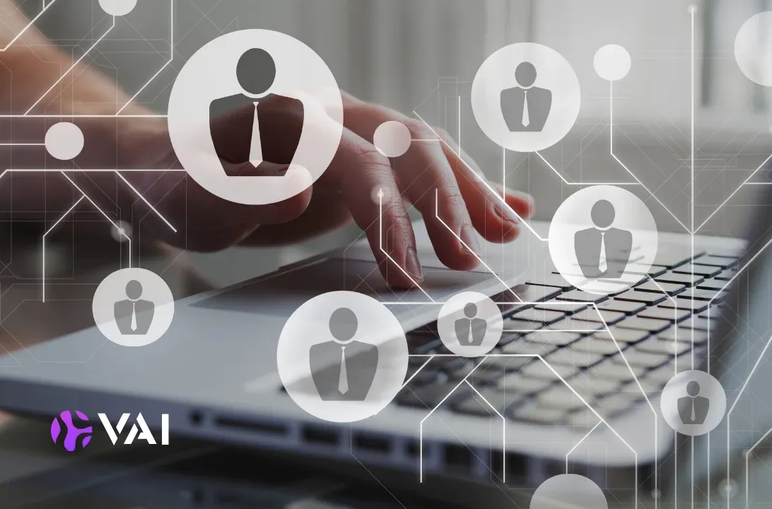Hands typing on a laptop surrounded by connected employee profile icons